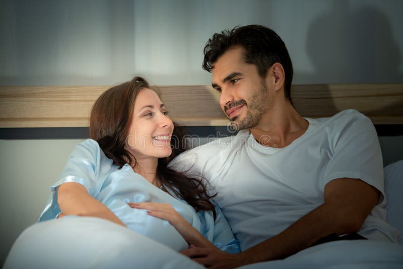 Gravid kvinna med man i sovrummet med en atmosfär av roligt att prata arkivbild