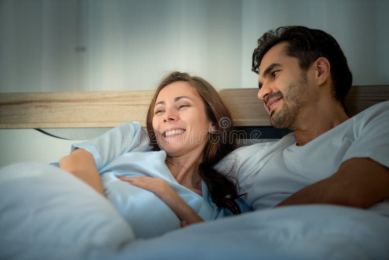 Gravid kvinna med man i sovrummet med en atmosfär av roligt att prata royaltyfri foto