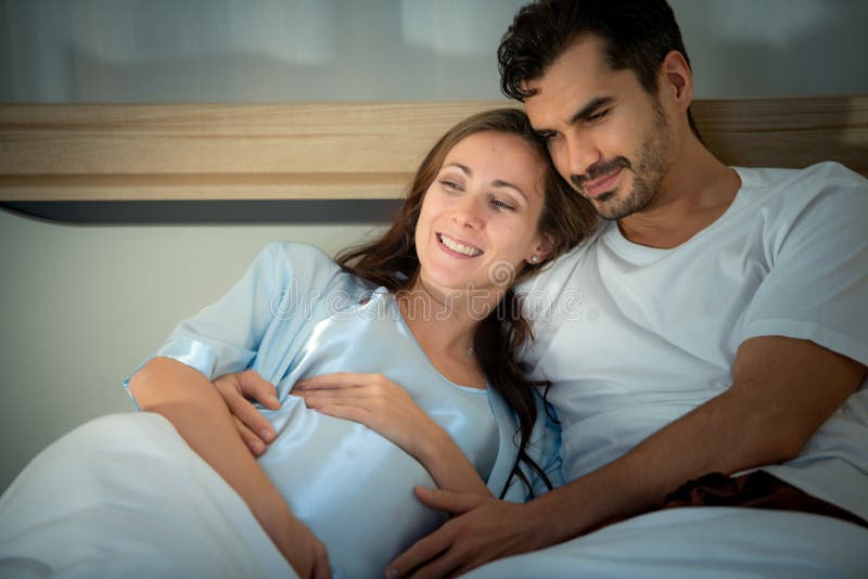 Gravid kvinna med man i sovrummet med en atmosfär av roligt att prata arkivbilder
