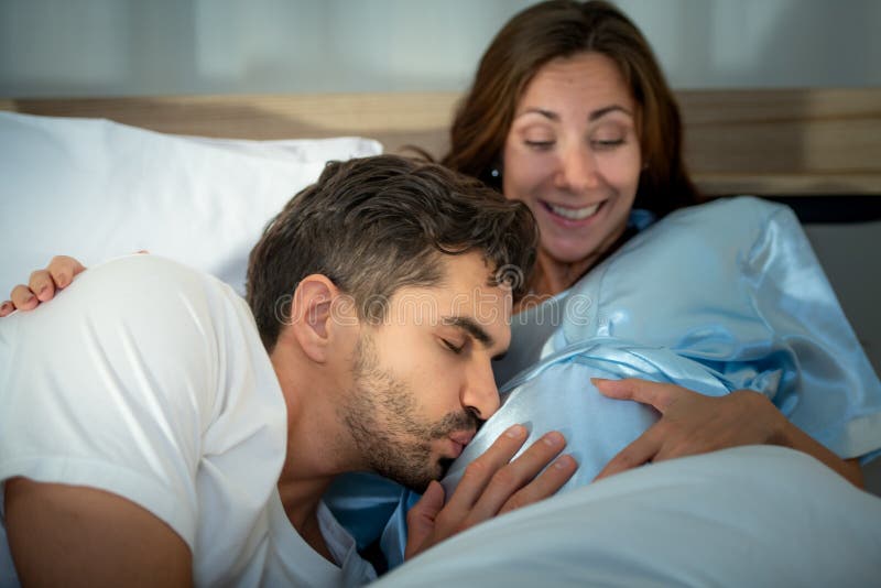Gravid kvinna med man i sovrummet med en atmosfär av roligt att prata royaltyfri bild
