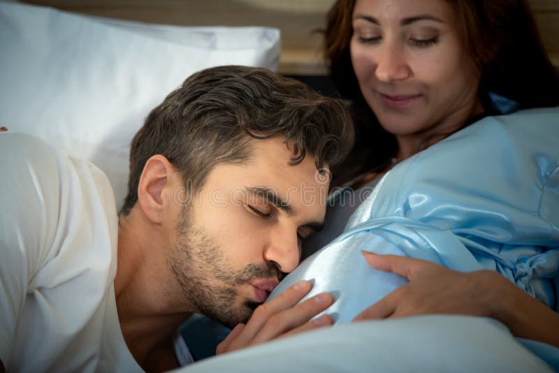 Gravid kvinna med man i sovrummet med en atmosfär av roligt att prata arkivfoton