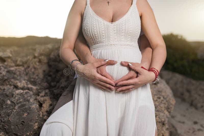 Gravid kvinna och hennes makeinnehavh?nder p? magen arkivbild Gravid kvinna och hennes makeinnehavh?nder p? magen arkivbild