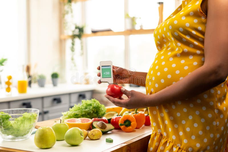 Gravid kvinna som framme står av köksbordet royaltyfri fotografi