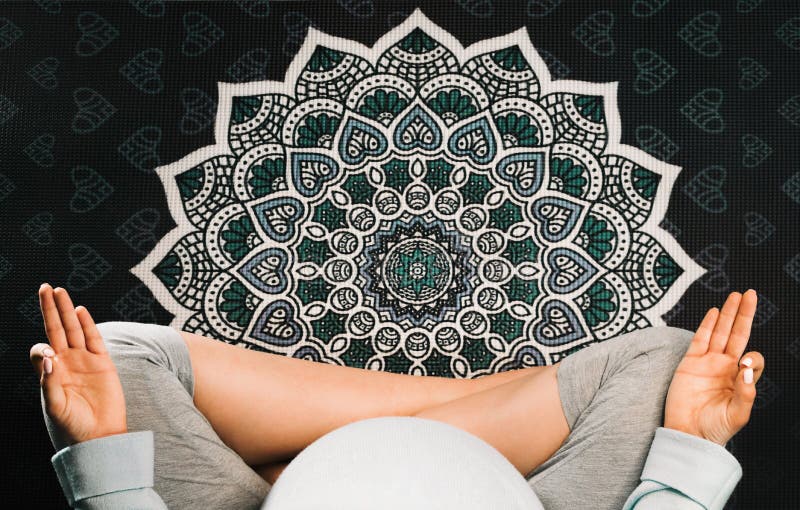 Gravid kvinna som sitter i lotusblommaposition på matt mandalayoga och att meditera Top beskådar arkivbild Gravid kvinna som sitter i lotusblommaposition på matt mandalayoga och att meditera Top beskådar arkivbild