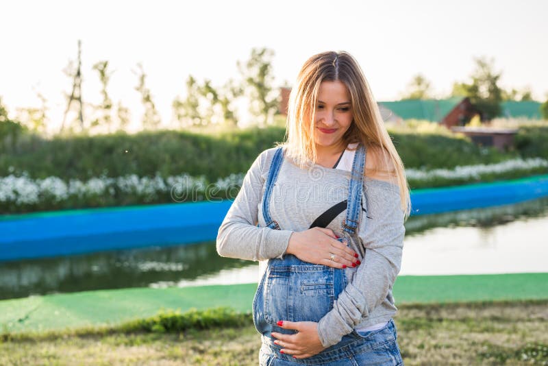 Gravid kvinna som utomhus kramar hennes mage
