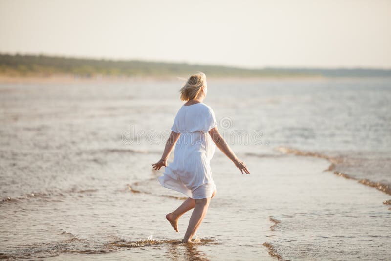Gravid kvinnabanhoppning på stranden Gladlynt kvinna som kör på kusten på hennes havandeskap på sommaraftonen royaltyfri bild Gravid kvinnabanhoppning på stranden Gladlynt kvinna som kör på kusten på hennes havandeskap på sommaraftonen royaltyfri bild