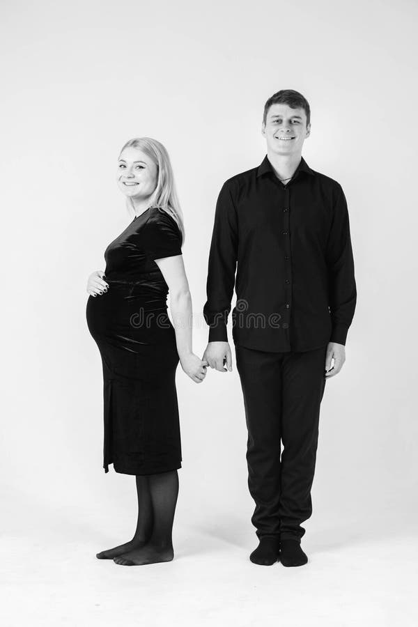 Gravida kvinnor och hennes make som håller händerna i svarta kläder på vit bakgrund Svartvit bild Snygg gift royaltyfria foton
