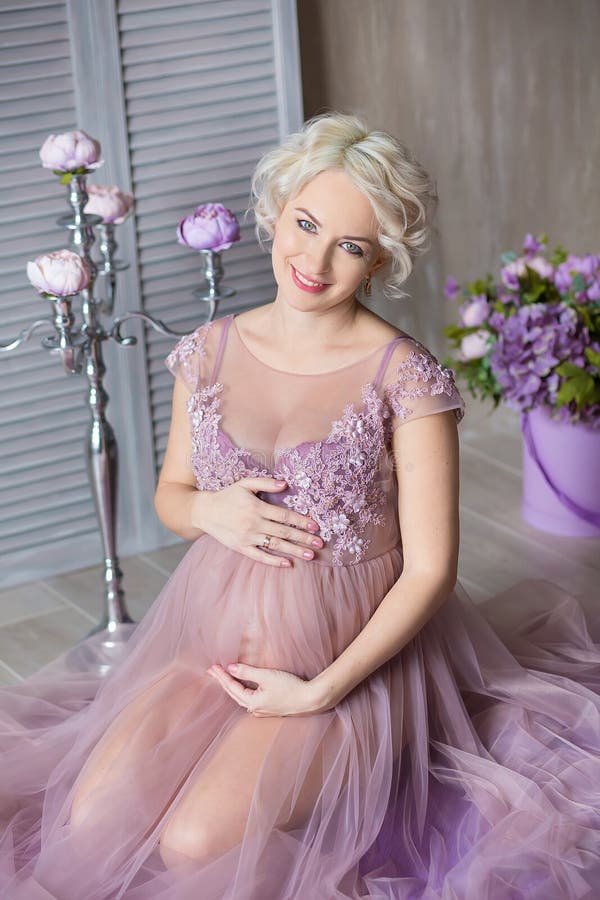 Gravidanza, maternità e concetto futuro felice della madre - donna incinta in vestito viola aerato con i fiori del mazzo contro v immagini stock Gravidanza, maternità e concetto futuro felice della madre - donna incinta in vestito viola aerato con i fiori del mazzo contro v immagini stock