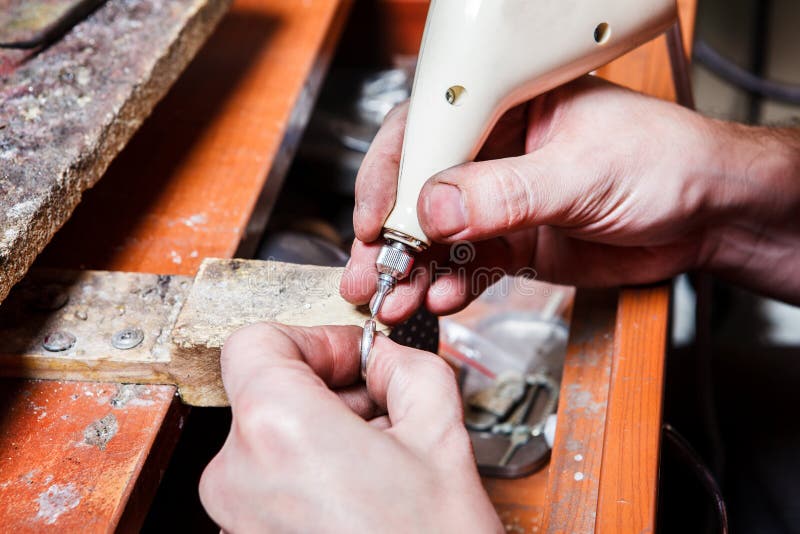 Jeweler's hands engraving on the ring. Jeweler's hands engraving on the ring