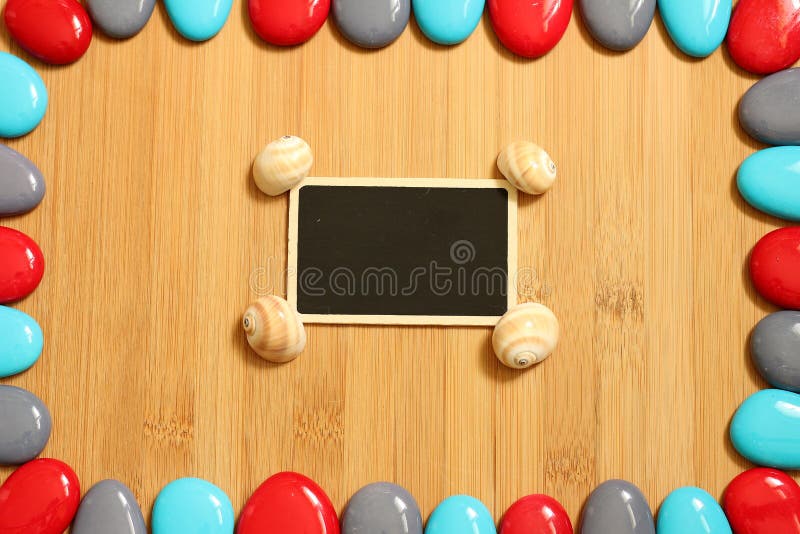Gray and blue red pebbles arranged all around a floor of brown bamboo wood with in the center a small empty slate to write a stock photo Gray and blue red pebbles arranged all around a floor of brown bamboo wood with in the center a small empty slate to write a stock photo