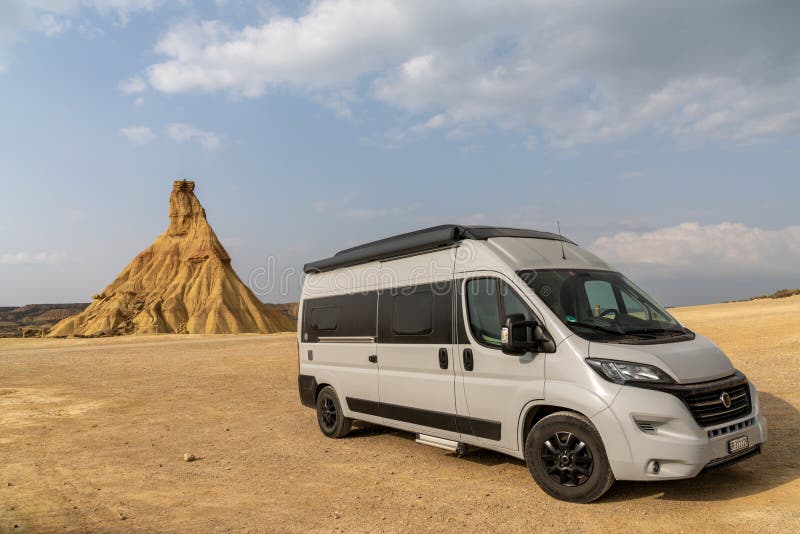 Gray camper van parked in the middle of the desert and wilderness with copy space