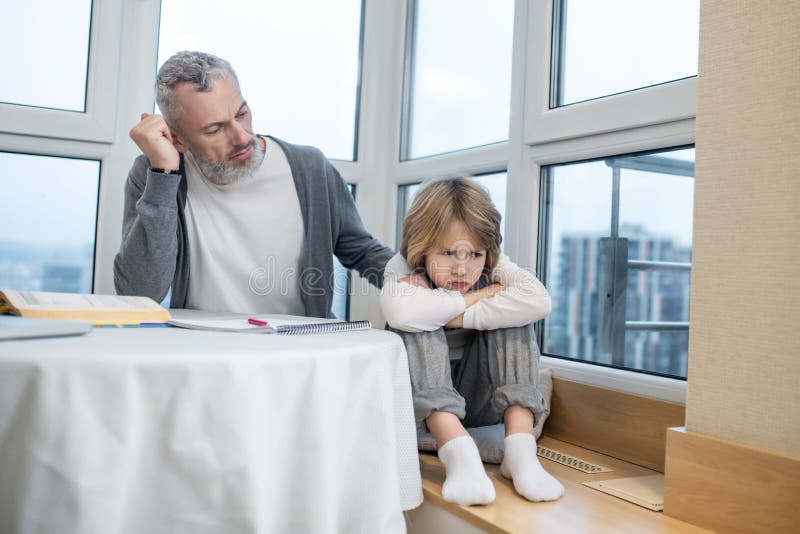 Gray-haired bearded man talking to his kid while he looking moody royalty free stock photos