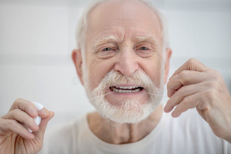 Gray Haired Man In White Tshirt Cleaning Teeth With A Floss Stock Image