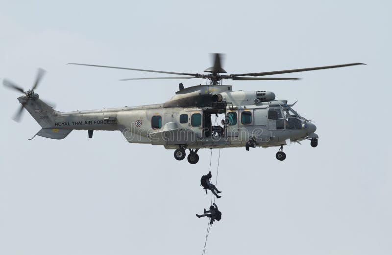 Gray helicopter in flight with blue sky background.