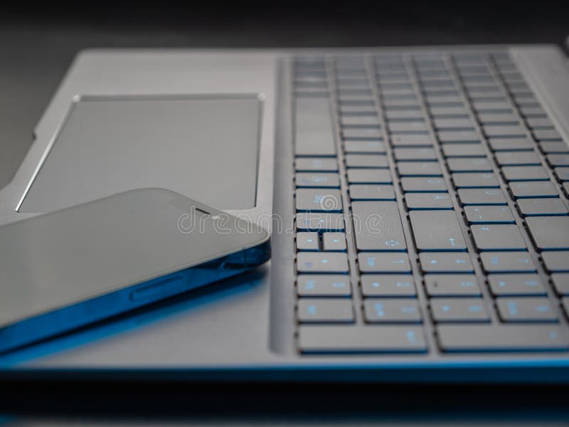 Gray laptop keyboard and smartphone close-up. Low angle view of computer key. Selective soft focus.