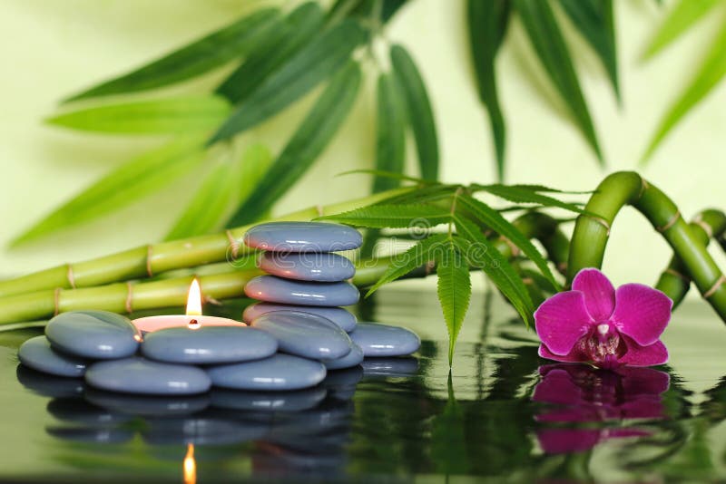 Gray pebbles arranged in Zen lifestyle with bamboo stalks, an orchid and a lighted candle royalty free stock photos Gray pebbles arranged in Zen lifestyle with bamboo stalks, an orchid and a lighted candle royalty free stock photos