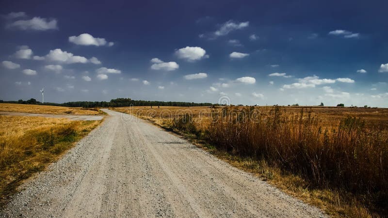 Gray Road entre la hierba de Brown debajo del cielo nublado blanco fotografía de archivo libre de regalías Gray Road entre la hierba de Brown debajo del cielo nublado blanco fotografía de archivo libre de regalías