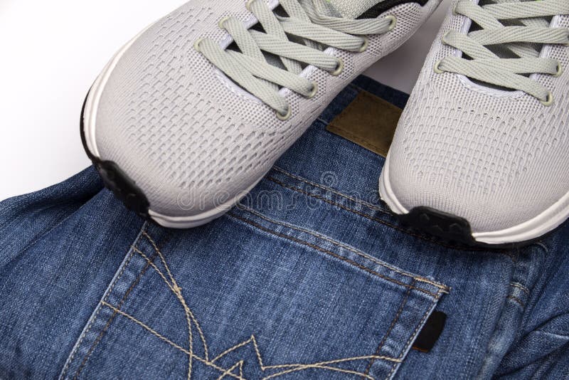 Partial view of woman in blue jeans and white shoes on grey background  Stock Photo by LightFieldStudios