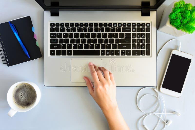 Gray wooden office desk table with laptop computer, smartphone,notebook, pen and cup of coffee.