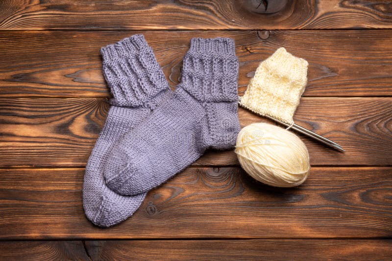 Gray woolen knitted socks and a ball of white thread with knitting needles on a wooden background royalty free stock photos Gray woolen knitted socks and a ball of white thread with knitting needles on a wooden background royalty free stock photos