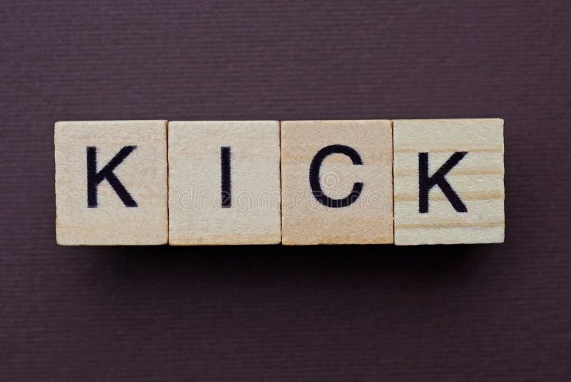 Gray word kick from small wooden letters on a brown table