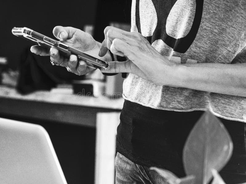 Grayscale shot of a person texting a friend using a smartphone royalty free stock photography