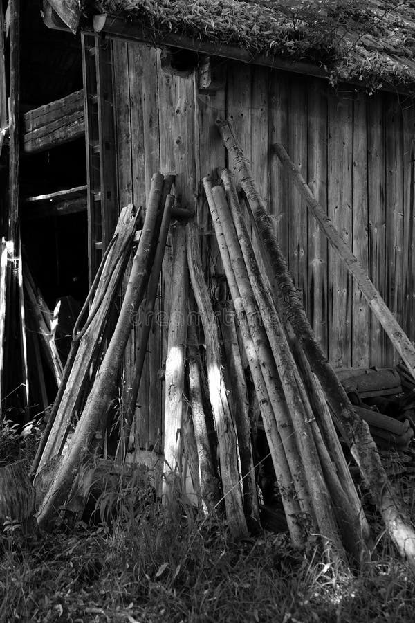 Grayscale shot of wooden planks leaning on an old wooden barn in a field royalty free stock photo