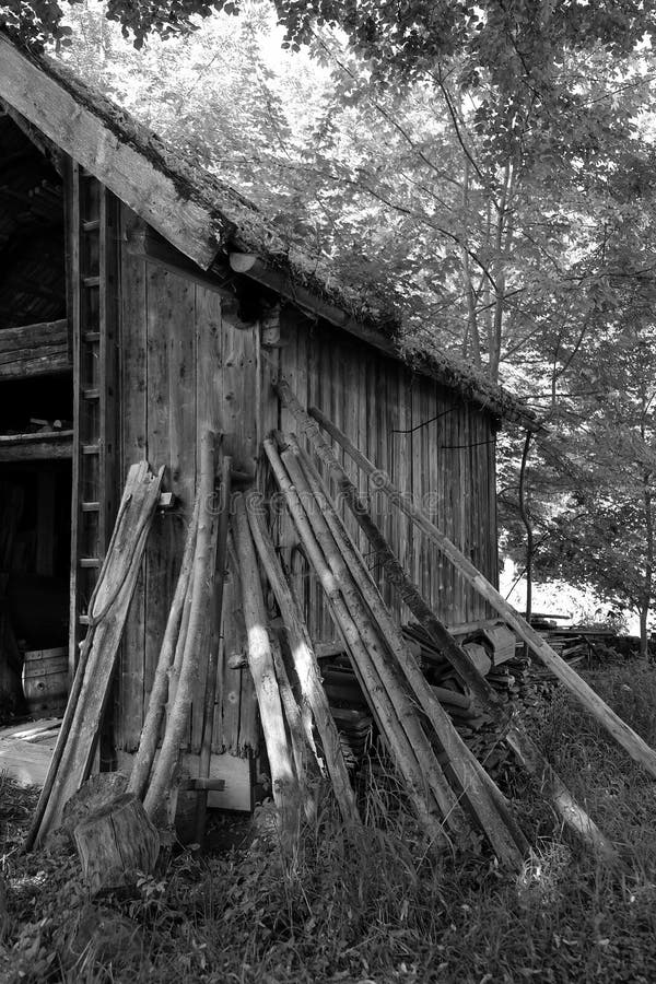 Grayscale shot of wooden planks leaning on an old wooden barn in a field royalty free stock images