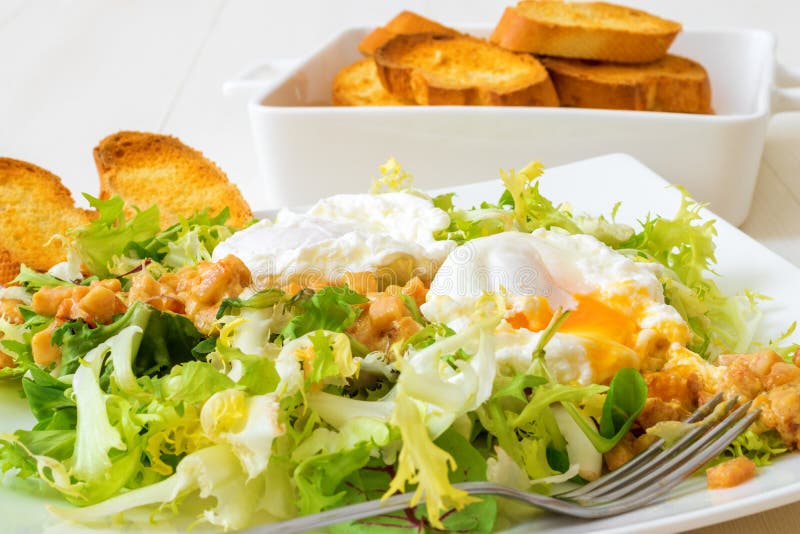 Great Salade Lyonnaise, French classic salad. Eggs, bacon, toasts.