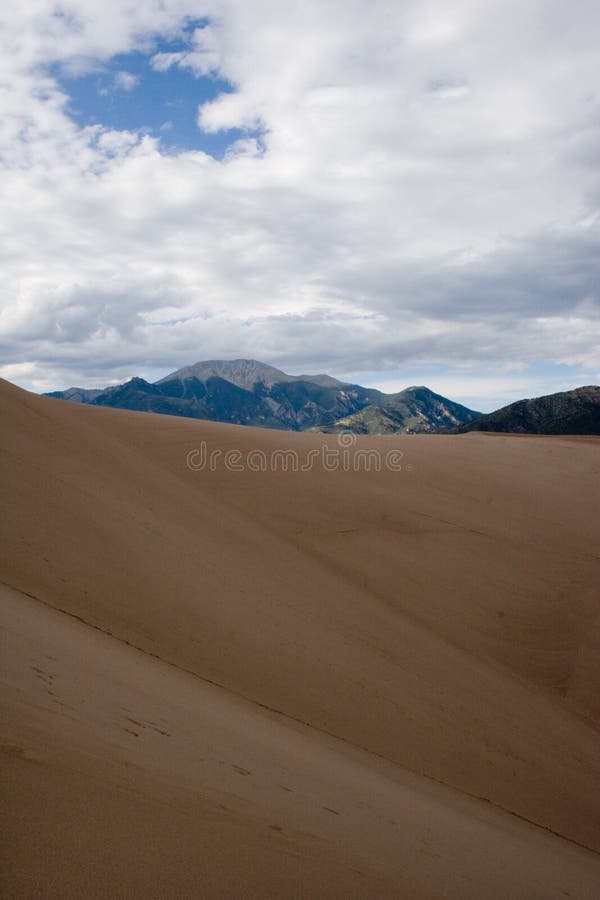 Sand, wind and erosion form patterns on the dunes at Great Sand Dunes National Monument with the Rocky Mountains in the background. Sand, wind and erosion form patterns on the dunes at Great Sand Dunes National Monument with the Rocky Mountains in the background.