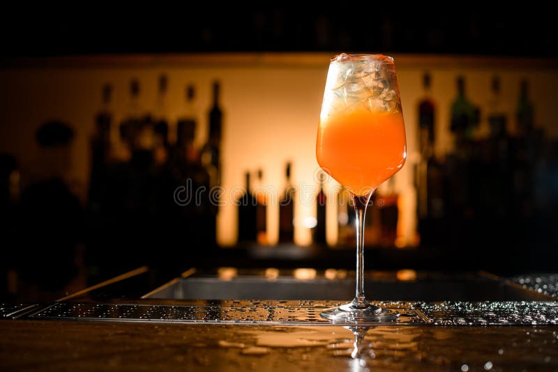 great view of glass with bright alcoholic drink and ice cubes on bar