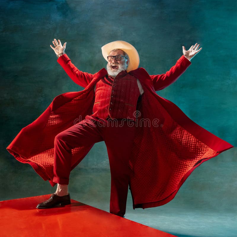 Modern stylish Santa Claus in red fashionable suit and cowboy`s hat on dark background