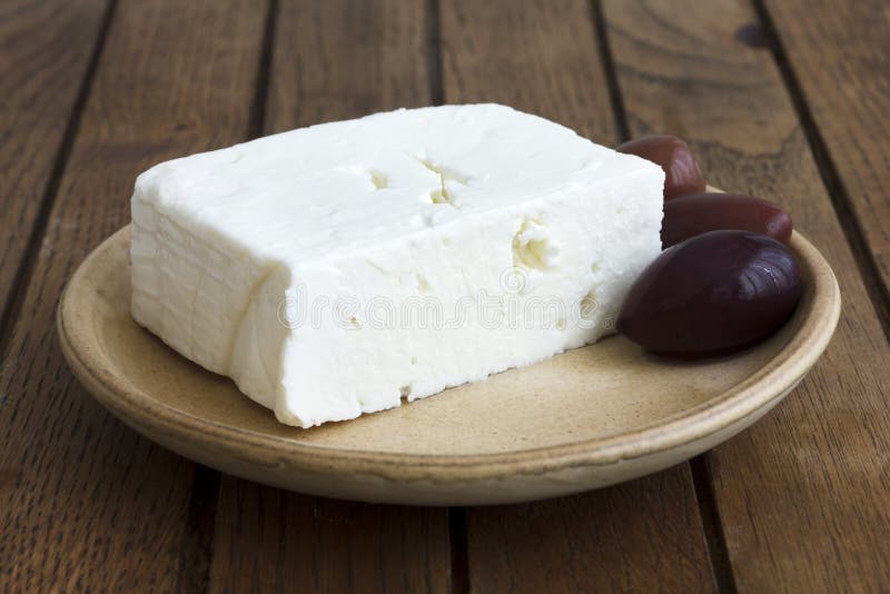 Grecki feta ser z Kalamata oliwkami na wieśniaka stole i talerzu fotografia stock Grecki feta ser z Kalamata oliwkami na wieśniaka stole i talerzu fotografia stock