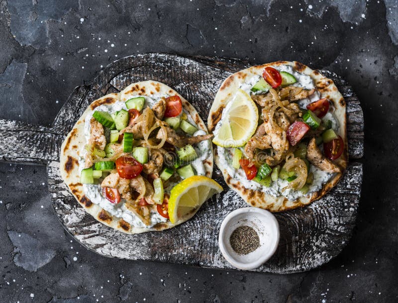 Greek Chicken Gyros Flatbread on a Rustic Cutting Board on a Dark Background, Top View Stock
