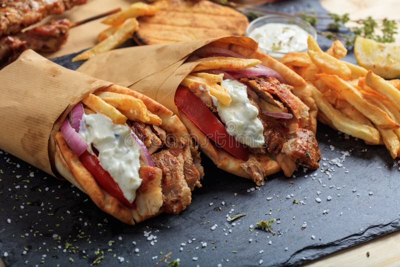 Greek gyros wrapped in pita breads on a black dish