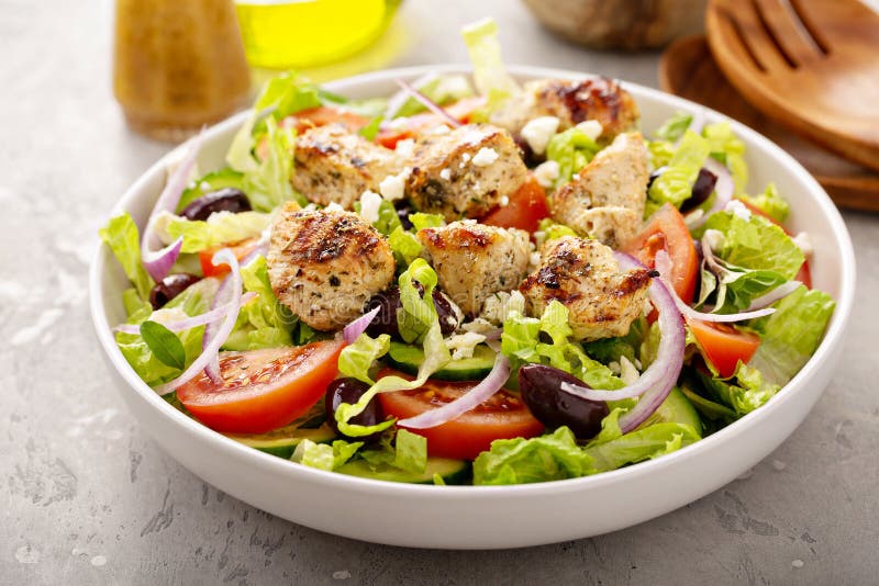 Greek salad with vinaigrette dressing topped with grilled chicken. Souvlaki royalty free stock images