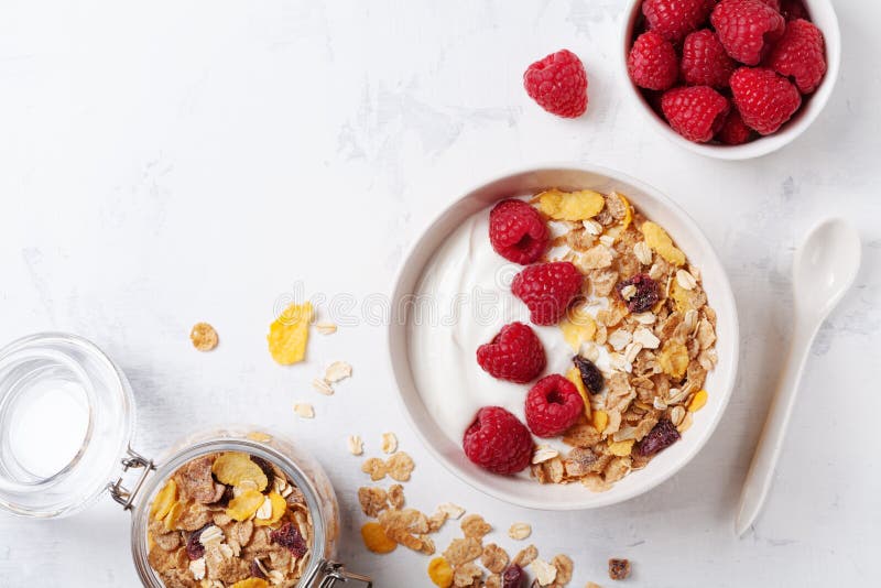 Greek yogurt in bowl with raspberries and muesli on white table top view. Healthy breakfast stock photos Greek yogurt in bowl with raspberries and muesli on white table top view. Healthy breakfast stock photos