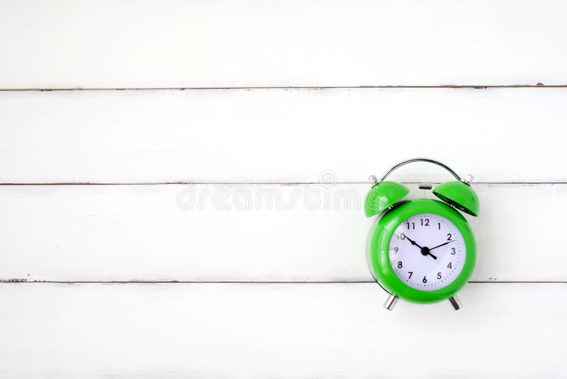 Green alarm clock on vintage white wood background royalty free stock image