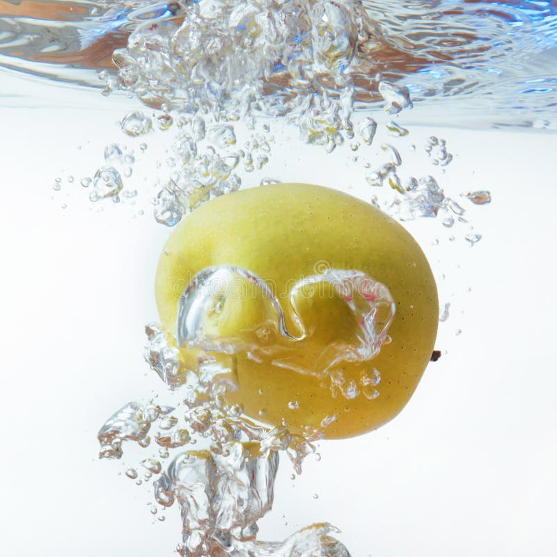 Green Apple Under Water with a Trail of Transparent Bubbles Stock Photo