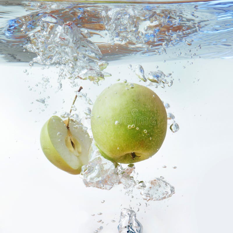 Green Apple Under Water with a Trail of Transparent Bubbles Stock Photo