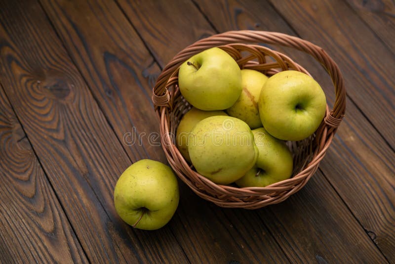 Green apples in the basket on wooden background