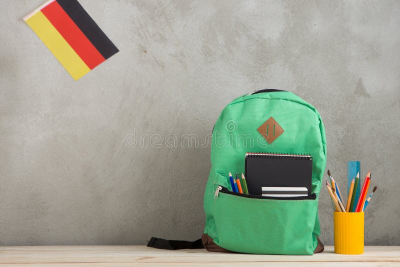 Green Backpack, Flag of the Germany, School Supplies Against a Cement