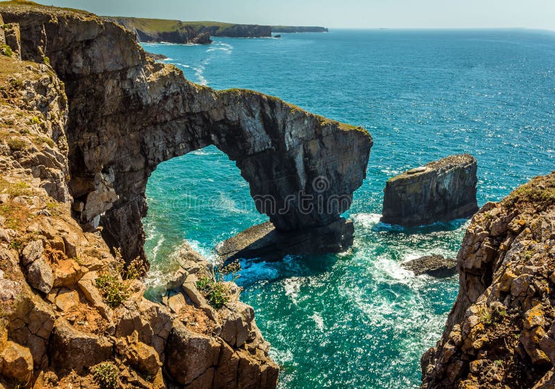 The Green Bridge of Wales with lichen-covered rocks in the foreground on the Pembrokeshire coast, near Castlemartin