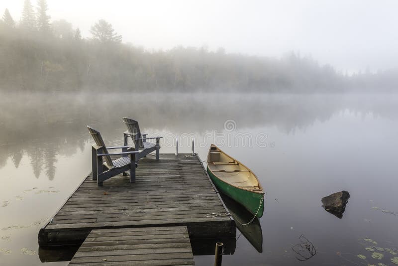 Green Canoe And Dock On A Misty Morning Stock Image