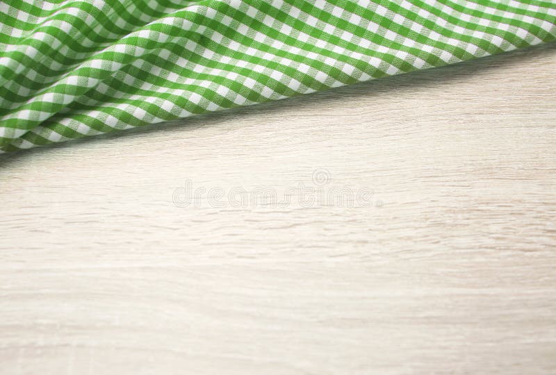 Green checered cloth on wooden table top view. Picnic towel on light wood texture background empty advertisement space