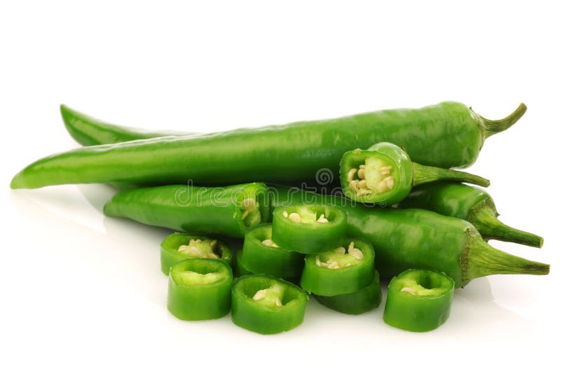 Bunch of fresh green chili peppers and some cut pieces on a white background