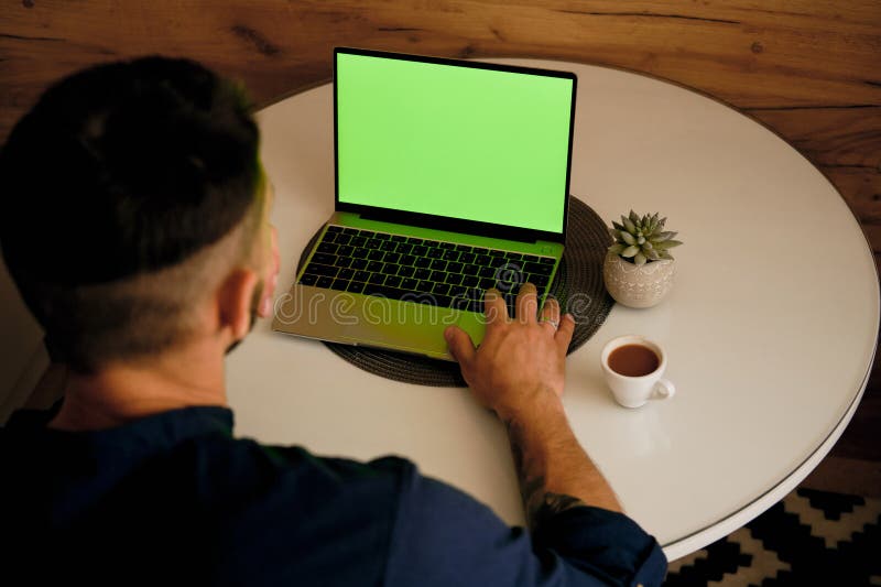 Green chromakey mock up image blank screen laptop with copy space background for advertising text. Young freelancer man using laptop on kitchen table at home. Marketing and creative design concept. Background chromakey copy space stock images, royalty-free photos and pictures
