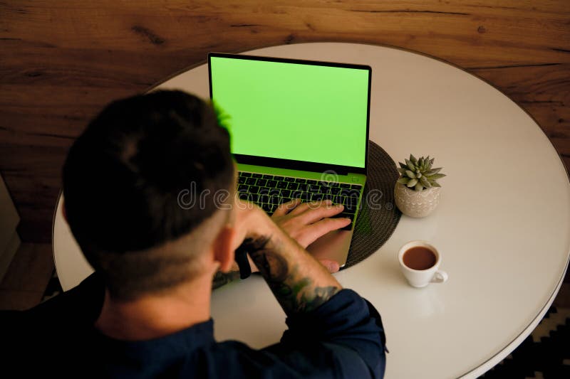 Green chromakey mock up image blank screen laptop with copy space background for advertising text. Young freelancer man using laptop on kitchen table at home. Marketing and creative design concept. Background chromakey copy space stock images, royalty-free photos and pictures