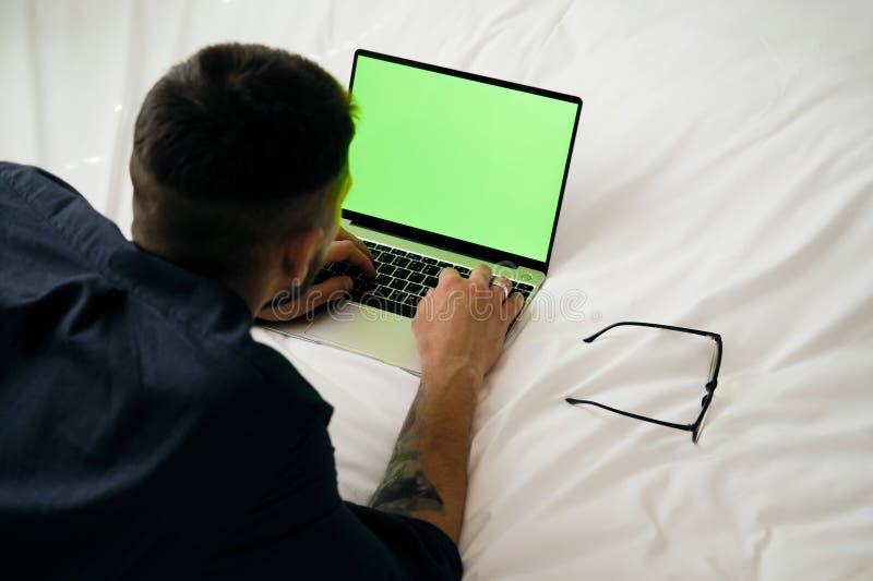 Green chromakey mock up image blank screen laptop with copy space background for advertising text. Young freelancer man using laptop on bed at home. Marketing and creative design concept. Background chromakey copy space stock images, royalty-free photos and pictures