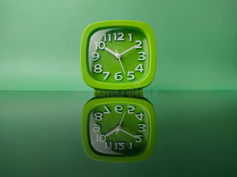Green clock on green background with reflection royalty free stock image